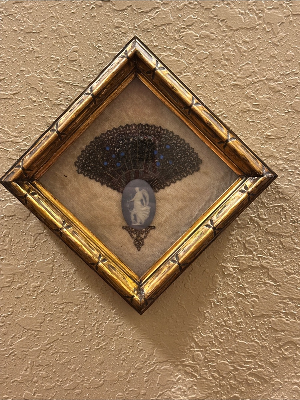 Vintage framed wall art piece featuring a small decorative folding fan